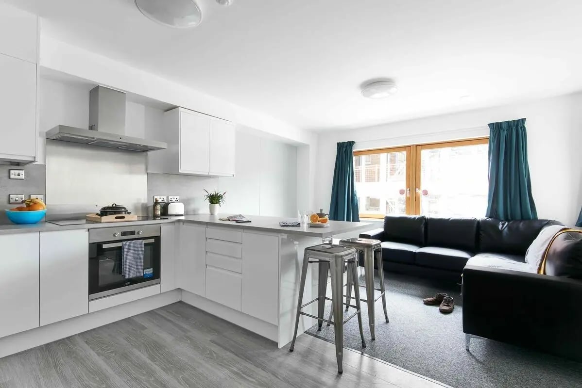 Kitchen island with stools and sofas living area at Bernard Myers House in London Student Accommodation