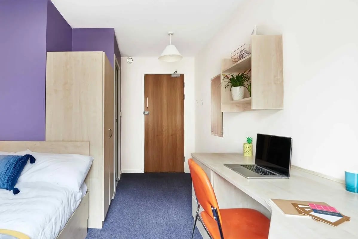 Bed wardrobe desk chair plants bedroom at Bernard Myers House in London Student Accommodation