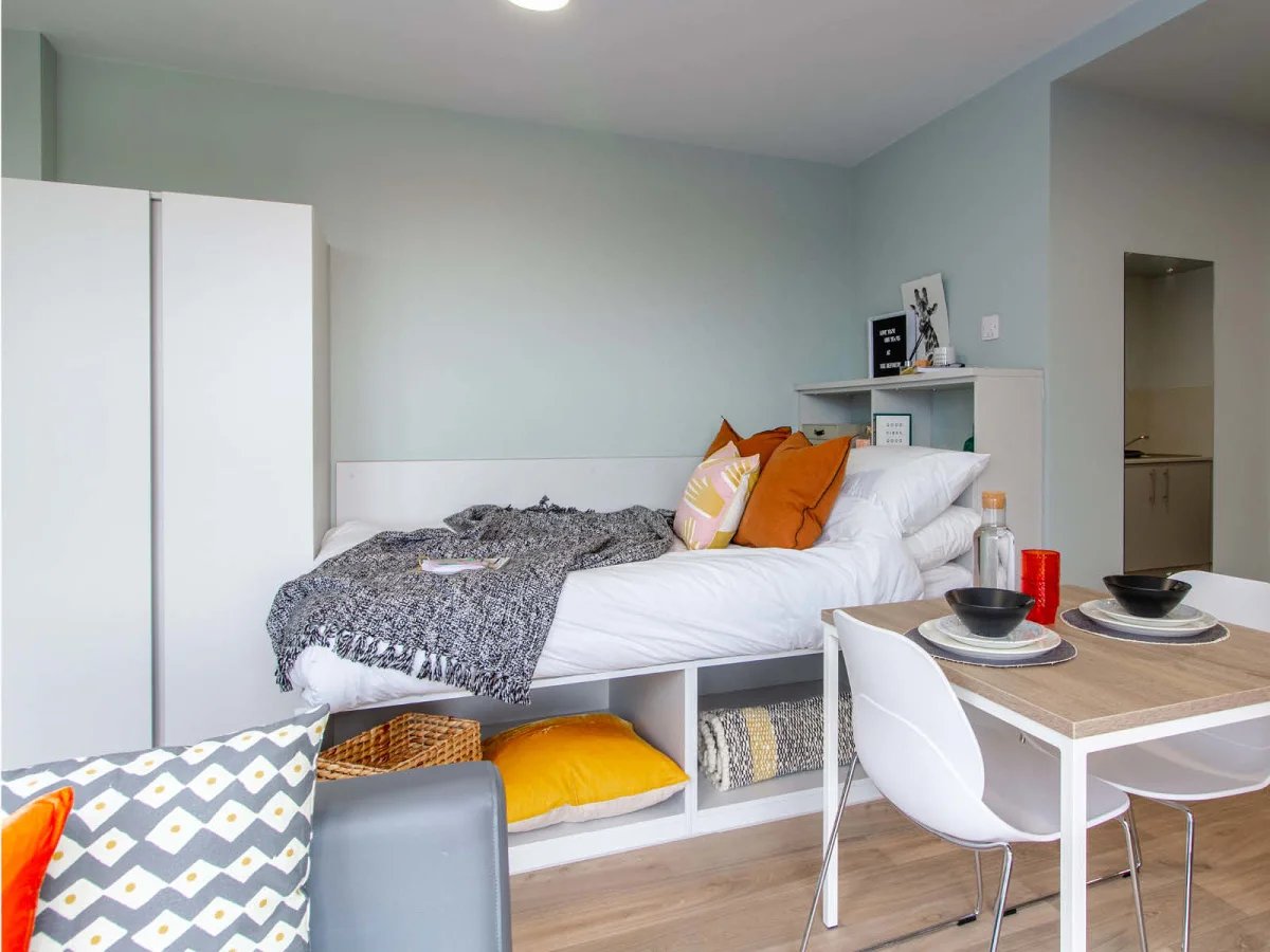 Bed with patterned throw study area and dining table Bedroom at The Refinery in Leeds Student Accommodation