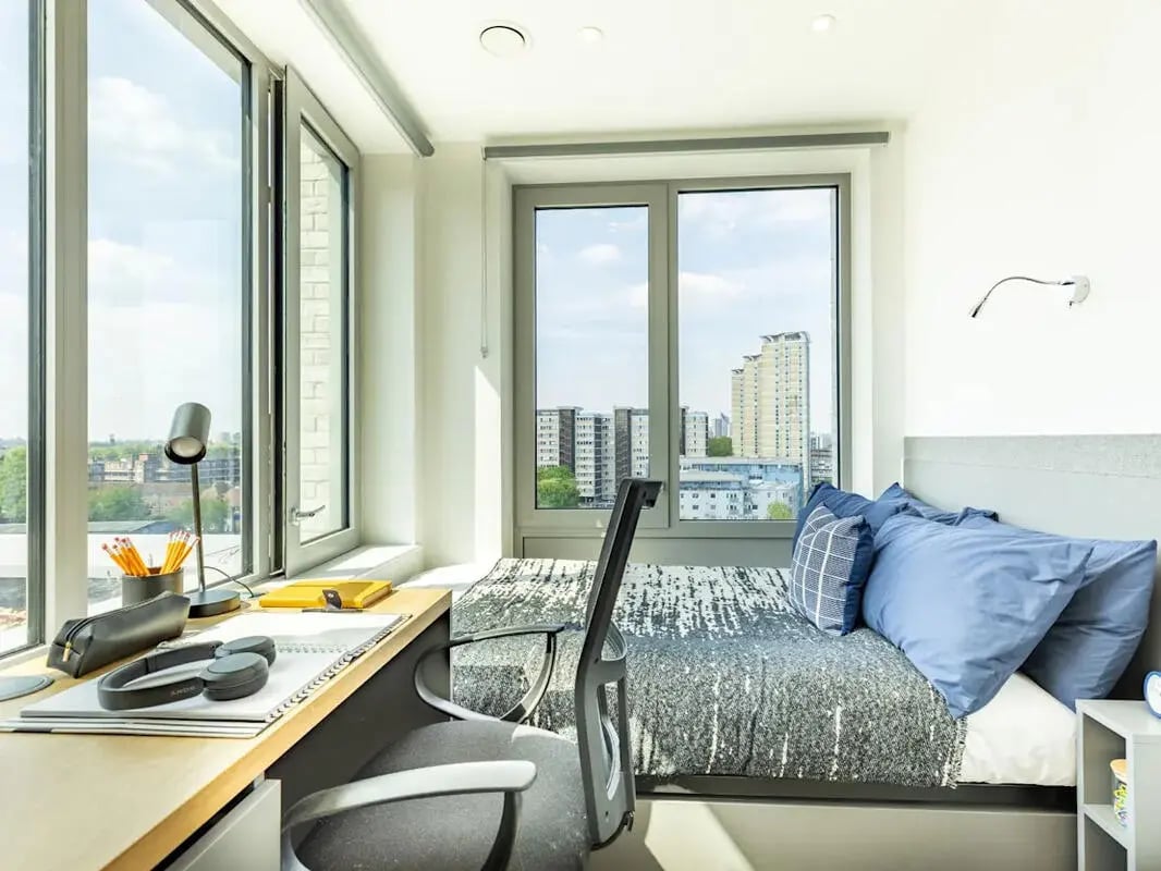 Desk with lamp headphones bed with pillows bedroom at Great Court in London Student Accommodation
