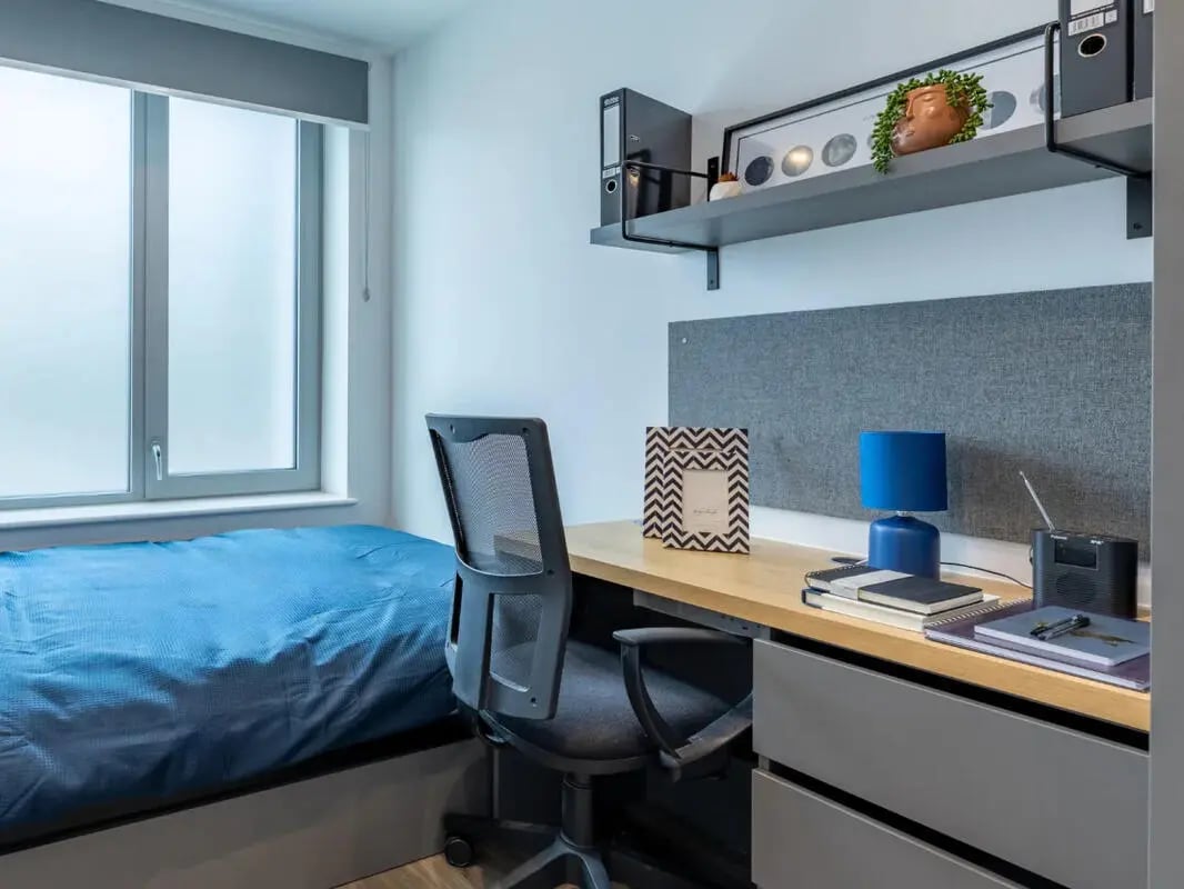 Bed desk chair lamp books and photo frame study area at Great Court in London Student Accommodation