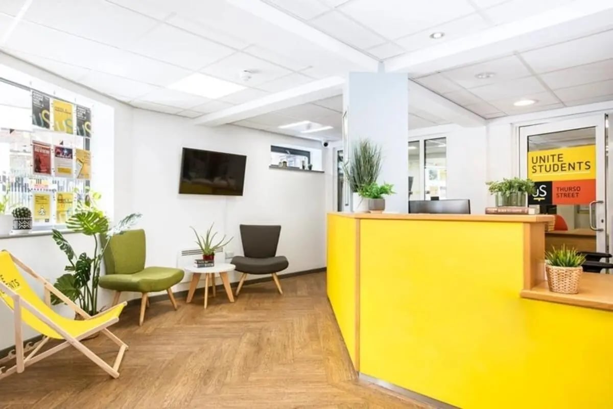 Yellow reception desk chairs plants television reception area at Thurso Street in Glasgow Student Accommodation