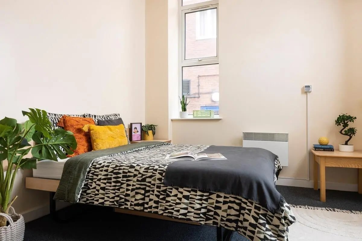 Bed with pillows, plants and side table bedroom at Lennon Studios in Liverpool Student Accommodation