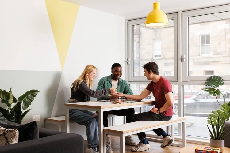 Three students playing board game at table living room at The Old Printworks in Edinburgh Student Accommodation