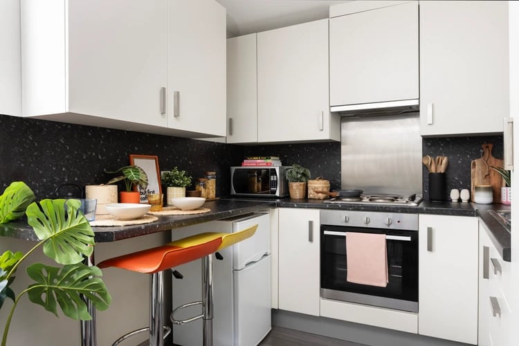 White cabinets bar stools fridge microwave oven kitchen at Salisbury court in Edinburgh Student Accommodation