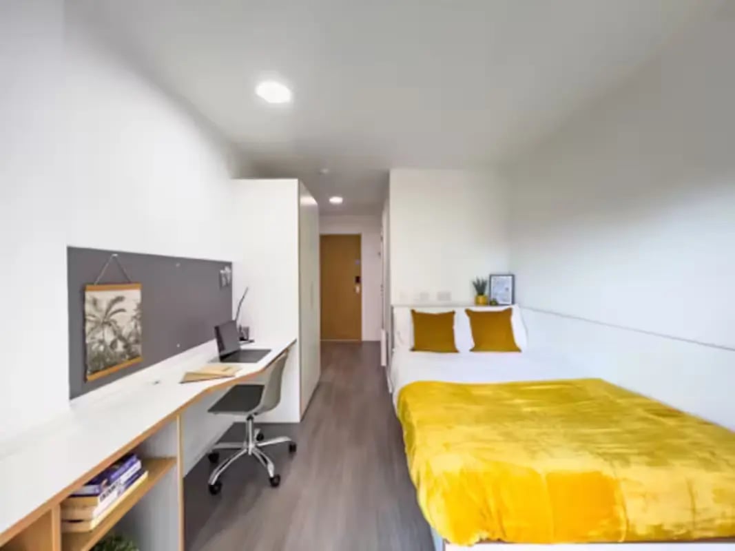 Bed desk chair and yellow blanket bedroom at Dobbie's Point in Glasgow Student Accommodation