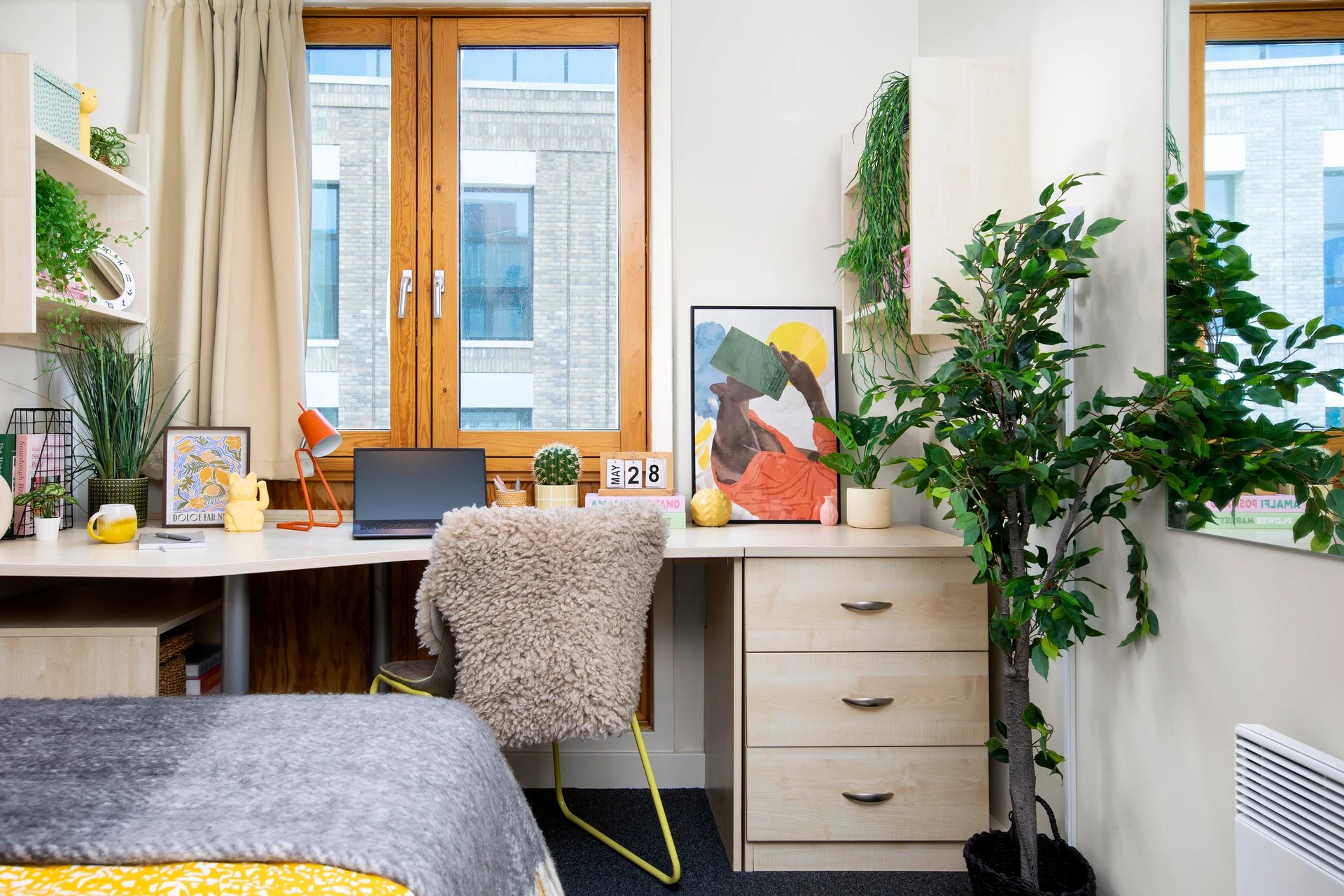 Desk laptop plant chair calendar artwork bedroom at Beaumont Court in London Student Accommodation
