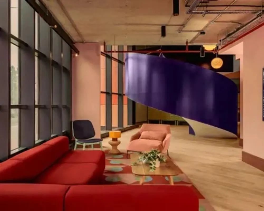 Red sofa coffee table chairs staircase living room at Scape Hammersmith in London Student Accommodation