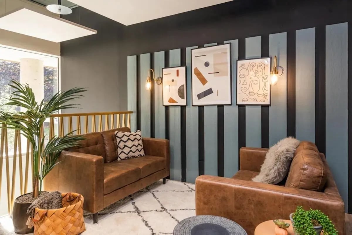 Brown leather sofas plants artwork living room at Hillfort House in Brighton Student Accommodation
