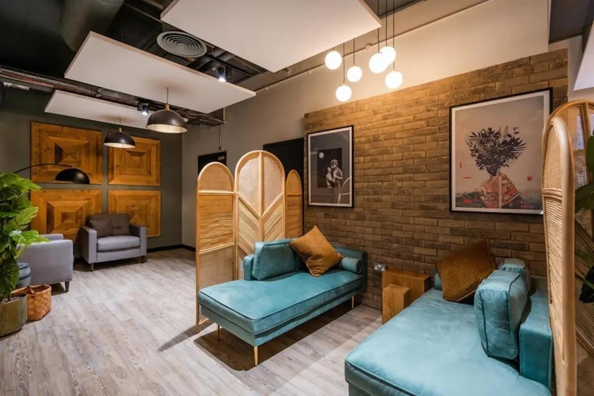 Teal chaise lounges artwork brick wall living room at Hillfort House in Brighton Student Accommodation