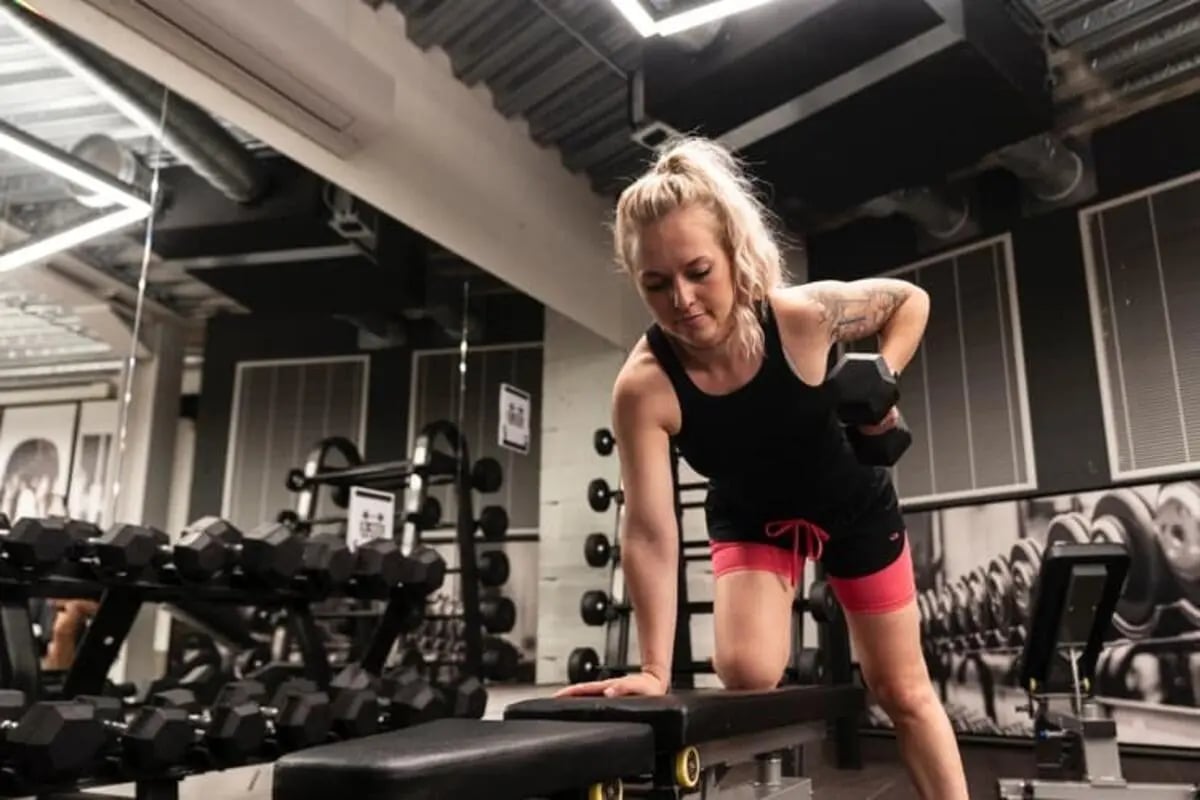 Woman lifting dumbbell on bench gym room at The Stay Club North Acton in London Student Accommodation