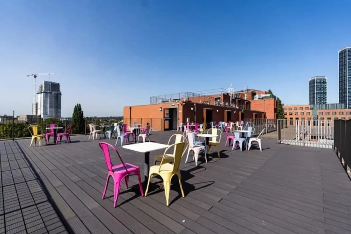 Colorful chairs and tables on rooftop terrace exterior at The Stay Club North Acton in London Student Accommodation