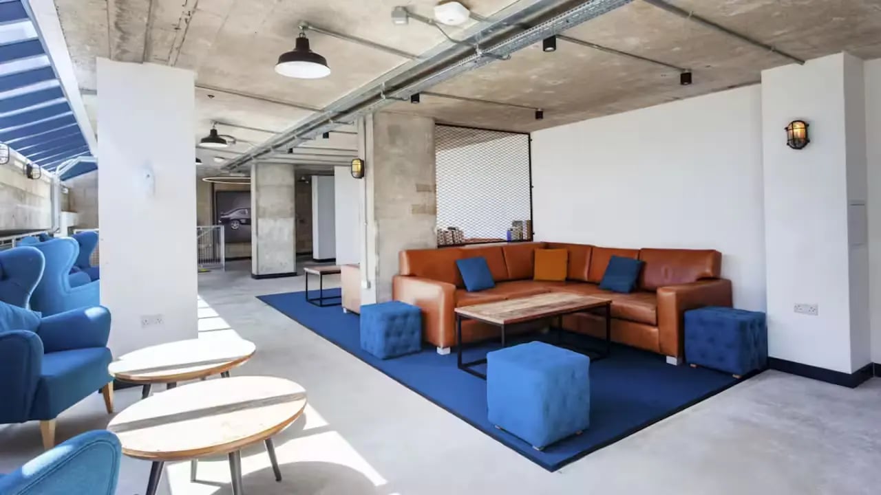 Brown sectional sofa blue chairs coffee tables living area at Berkshire House Reading in Reading Student Accommodation