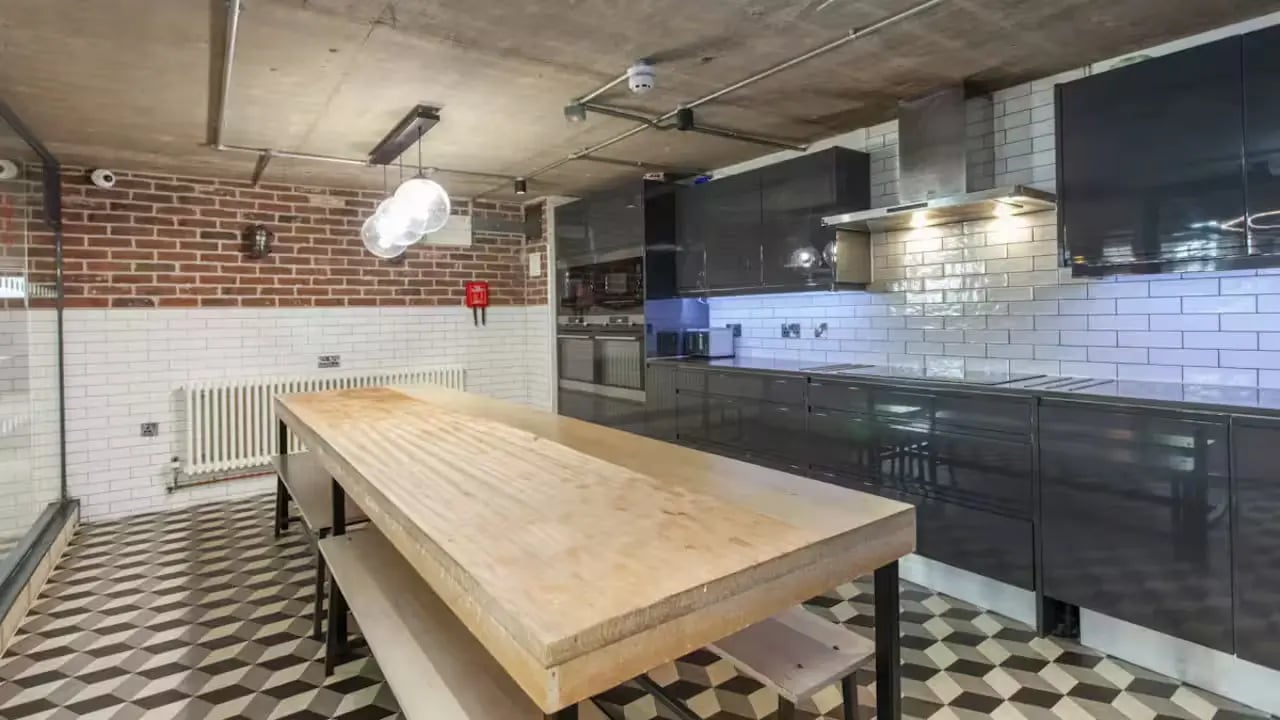 Communal kitchen with large wooden table and benches kitchen at Berkshire House Reading in Reading Student Accommodation