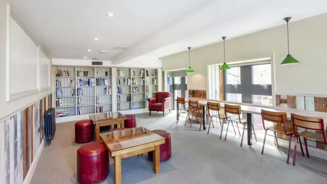 Bookshelves red chairs tables ottomans common area at Gillows in Lancaster Student Accommodation