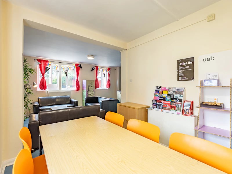 Dining table orange chairs leather sofas living room at Brooke Hall in London Student Accommodation
