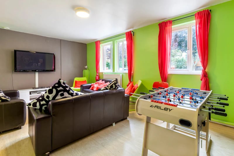 Foosball table sofas television and green walls living room at Brooke Hall in London Student Accommodation