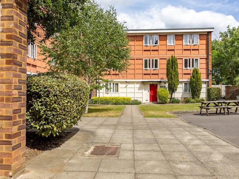 Brick building with red door and picnic tables exterior at Brooke Hall in London Student Accommodation