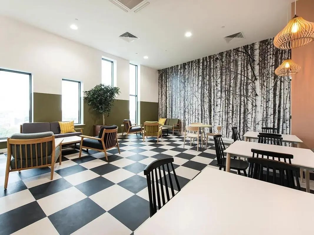 Sofas chairs tables with birch tree wallpaper communal area at Yugo Catherine House in Portsmouth Student Accommodation