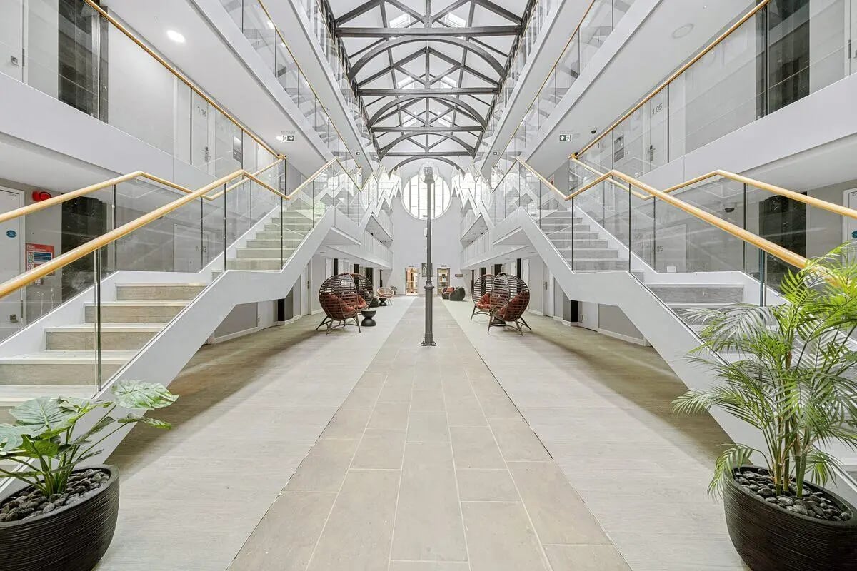 Corridor with symmetrical stairs and modern seating common area at Cathedral Park in Bristol Student Accommodation