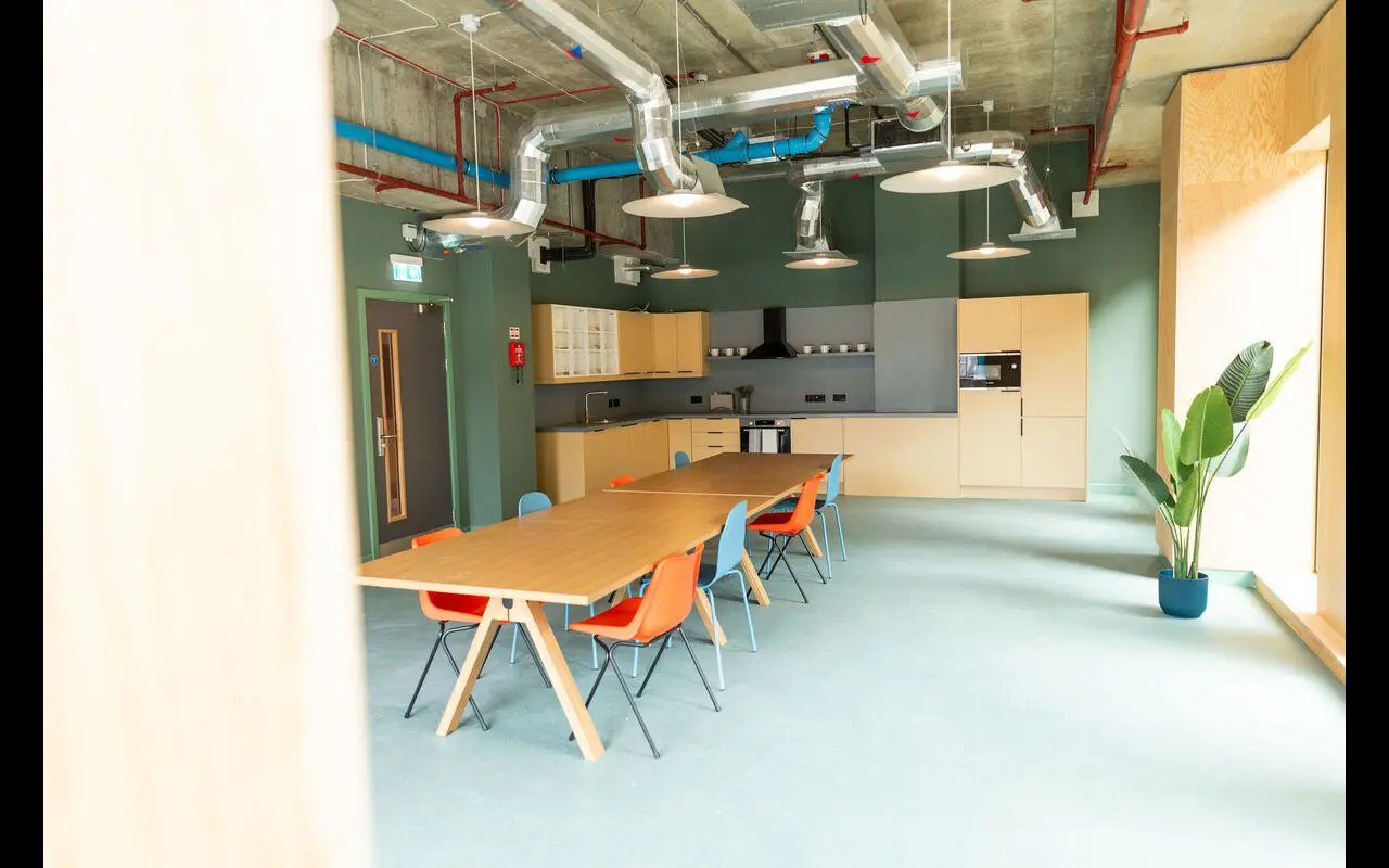 Wooden tables chairs kitchen area with appliances communal space at Martha Street Apartments in Glasgow Student Accommodation