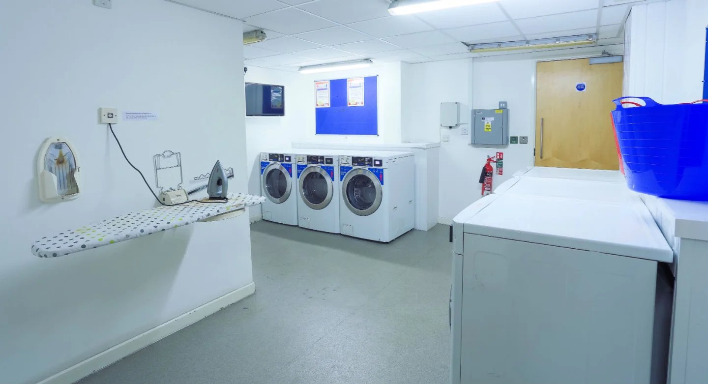 Ironing board washing machines fire extinguisher laundry room at Griffon Studios in London Student Accommodation