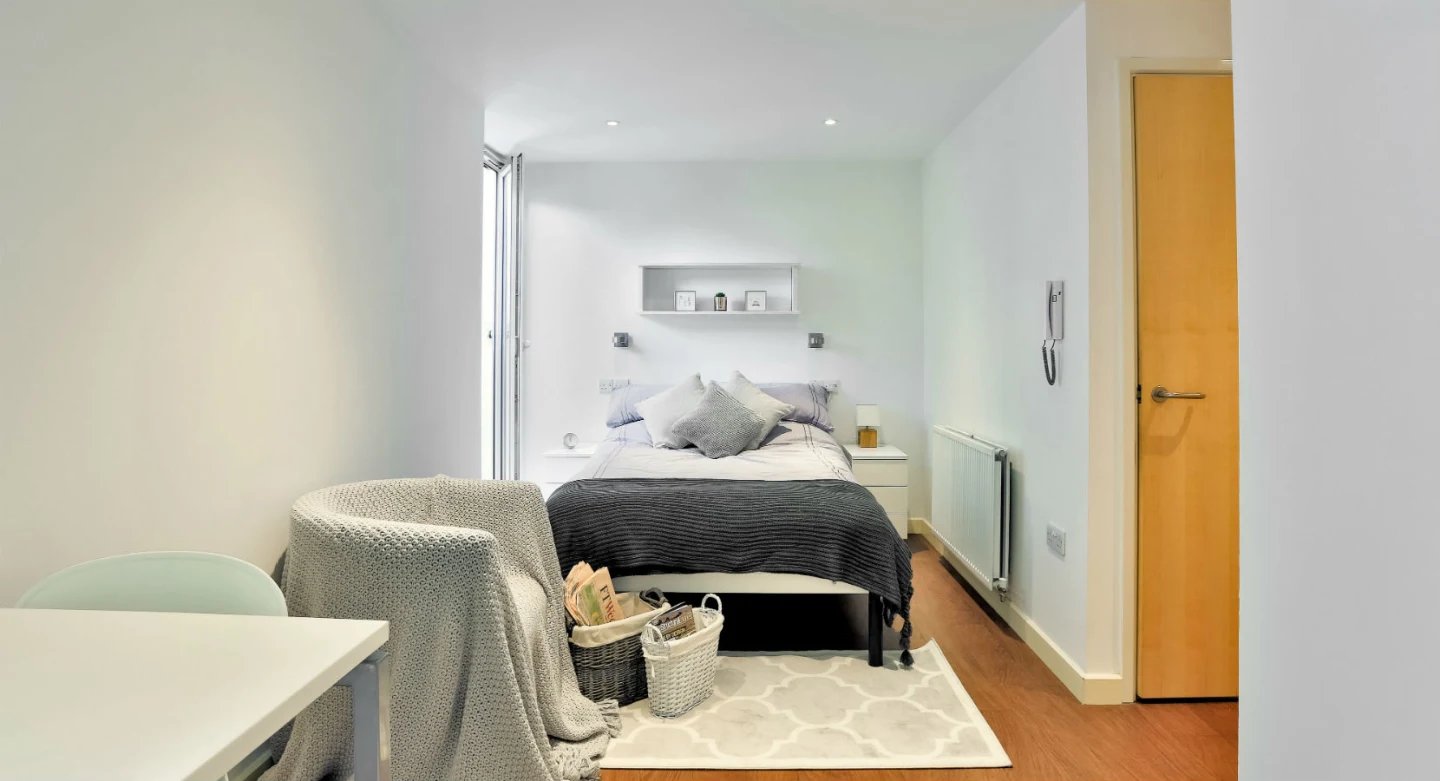 Bed chair table baskets rug bedroom at Griffon Studios in London Student Accommodation