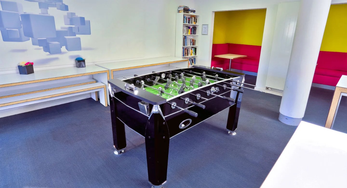 Foosball table with seating and bookshelf communal area at Griffon Studios in London Student Accommodation