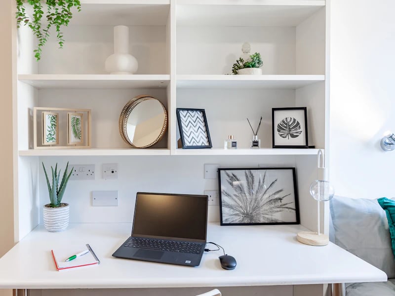 Desk with laptop plant and framed art study area at Academic House in London Student Accommodation