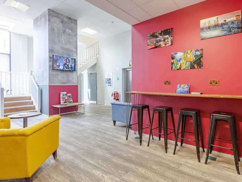 Yellow sofa counter with stools living area at Academic House in London Student Accommodation