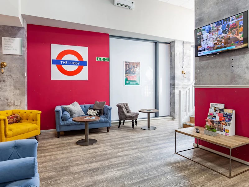Sofa chairs coffee tables magazine rack TV lobby at Academic House in London Student Accommodation