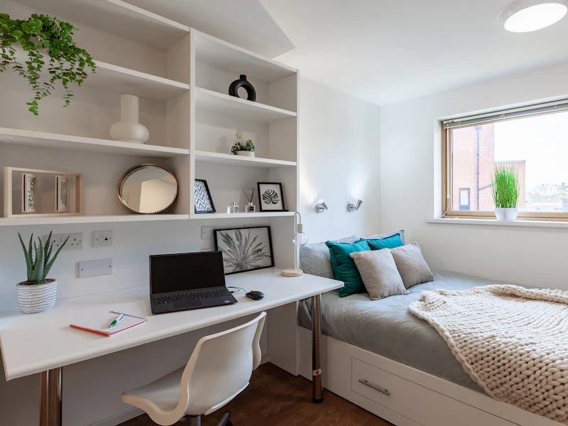 Desk with laptop bed with pillows study area at Academic House in London Student Accommodation