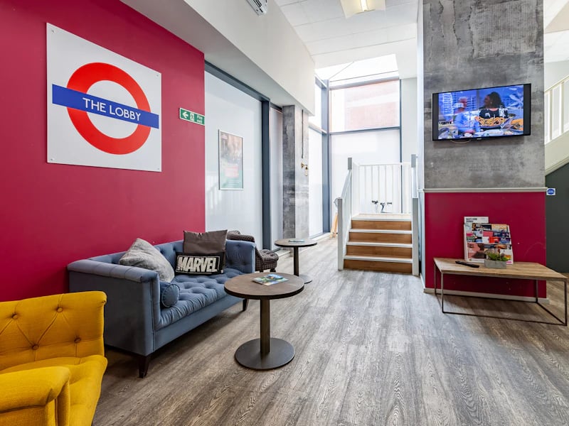 Blue sofa with Marvel pillow lobby living area at Academic House in London Student Accommodation