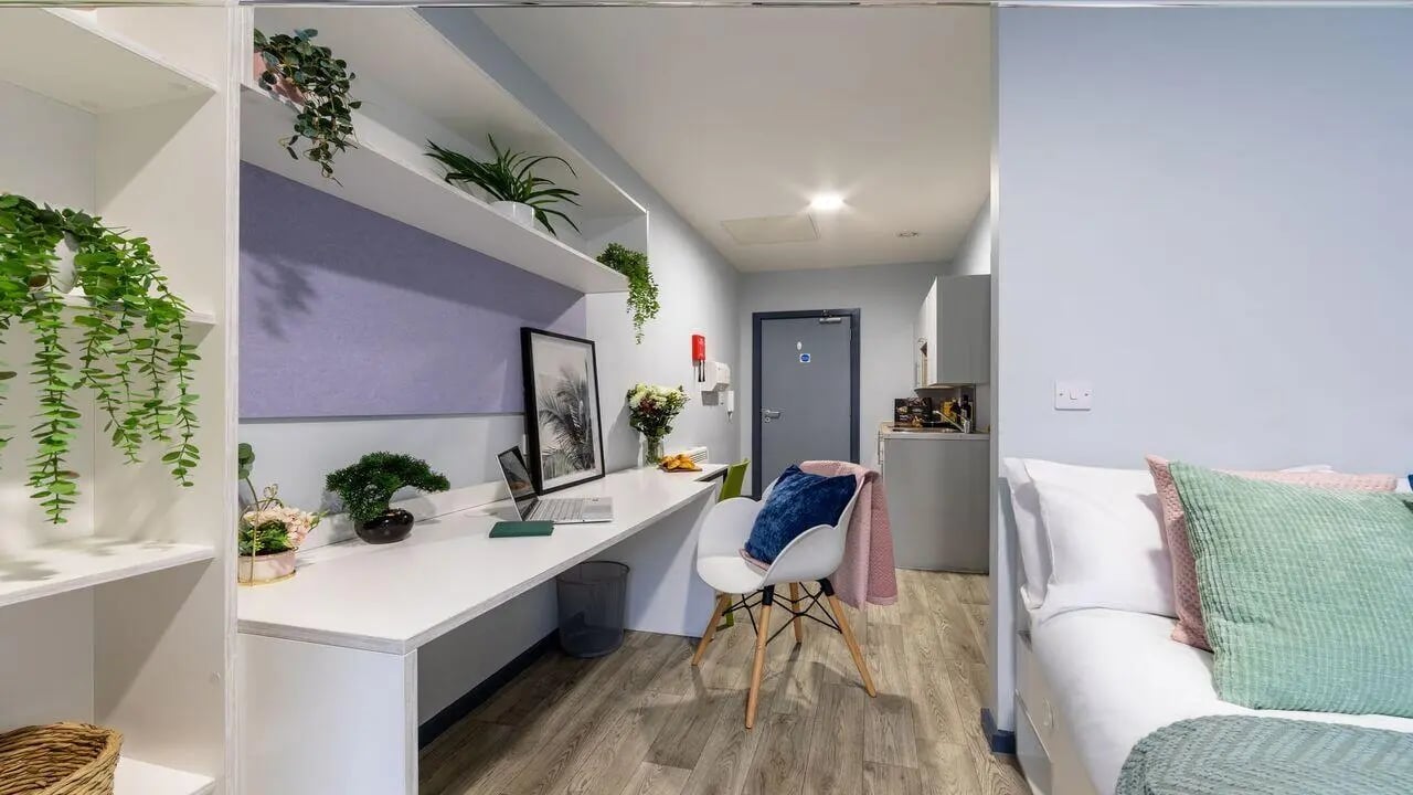 Desk laptop plants chair then kitchen studio at dwell Archer House in Nottingham Student Accommodation