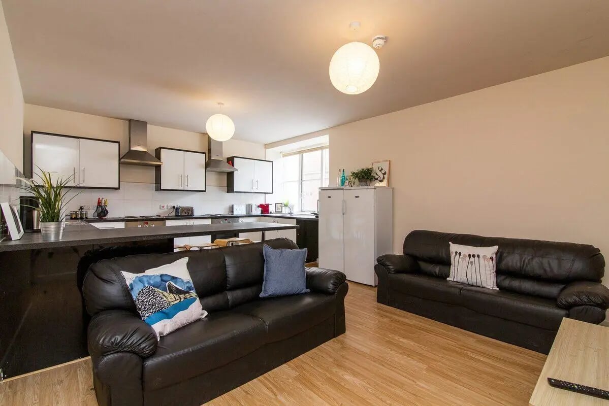 Two black sofas kitchen area white cabinets living room at dwell Castle Gate Haus in Nottingham Student Accommodation