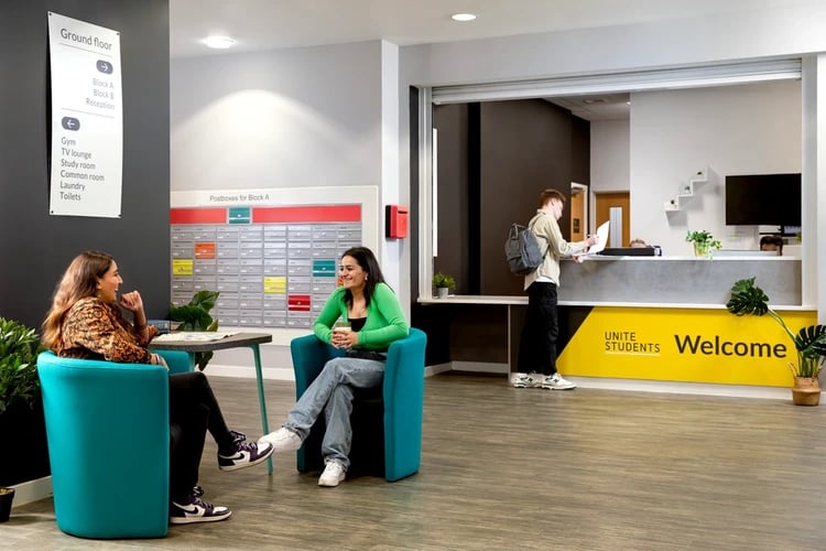 Two students sit in chairs by postboxes reception area at Orion Point in Southampton Student Accommodation