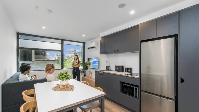 Sofa table kitchen cabinets refrigerator living room at UniLodge Melbourne Flagstaff in Melbourne Student Accommodation