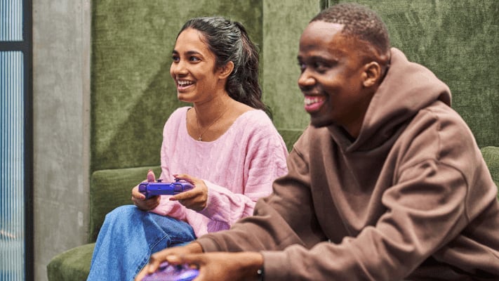 Two students playing video games on couch living room at UniLodge Melbourne Flagstaff in Melbourne Student Accommodation