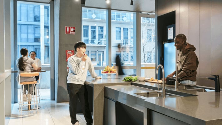 Students at kitchen island with fruit and sink kitchen at UniLodge Melbourne Flagstaff in Melbourne Student Accommodation