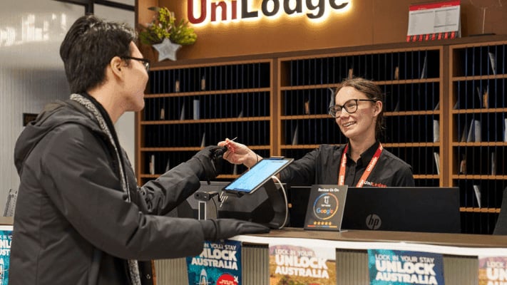 Reception desk with tablet and staff interacting Reception area at UniLodge Melbourne Flagstaff in Melbourne Student Accommodation