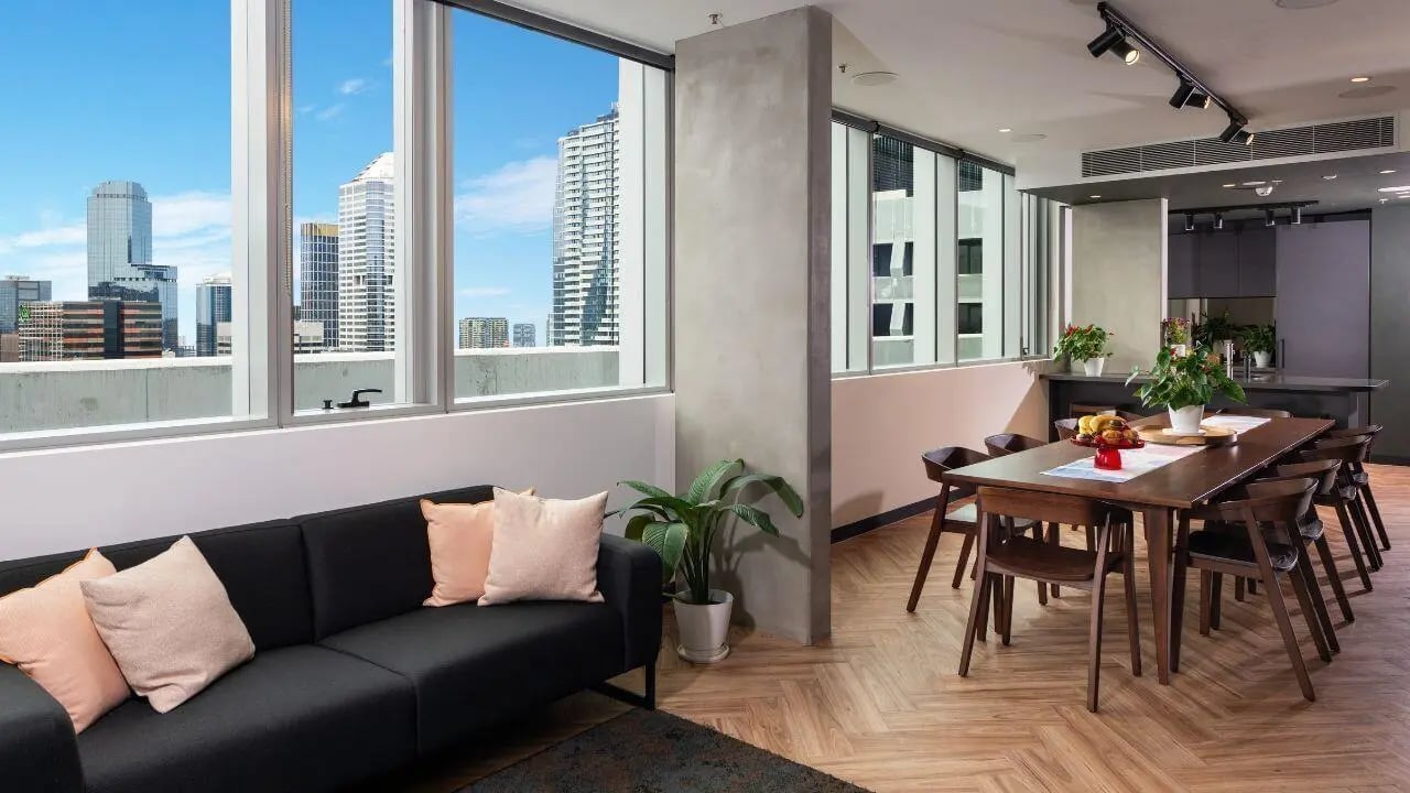 Black sofa with pillows dining table chairs living room at UniLodge Melbourne Flagstaff in Melbourne Student Accommodation