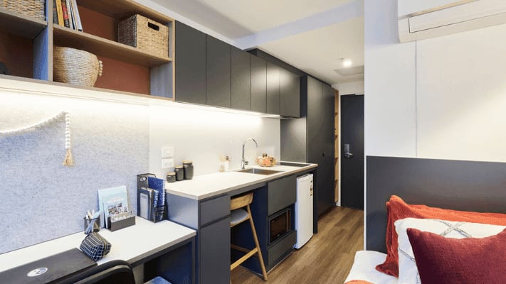Desk kitchen bed and shelves student studio apartment at UniLodge Melbourne Flagstaff in Melbourne Student Accommodation
