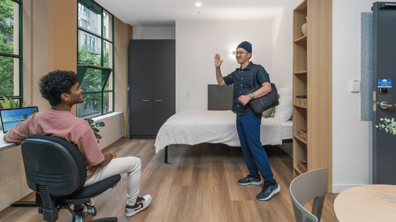 Two students in a bedroom with desk and bed at UniLodge Melbourne Flagstaff in Melbourne Student Accommodation