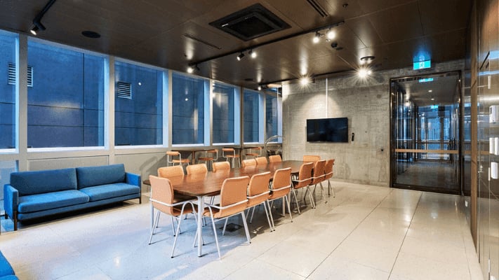 Conference table orange chairs blue couch television common room at UniLodge Melbourne Flagstaff in Melbourne Student Accommodation
