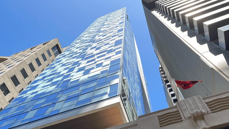 Modern glass building with red UniLodge flag exterior at UniLodge Melbourne Flagstaff in Melbourne Student Accommodation