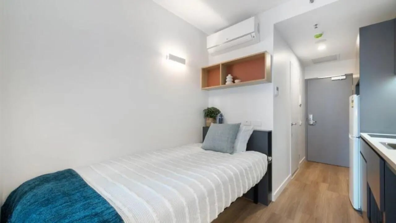 Bed with blue throw pillow and shelves bedroom at UniLodge Melbourne Central in Melbourne Student Accommodation