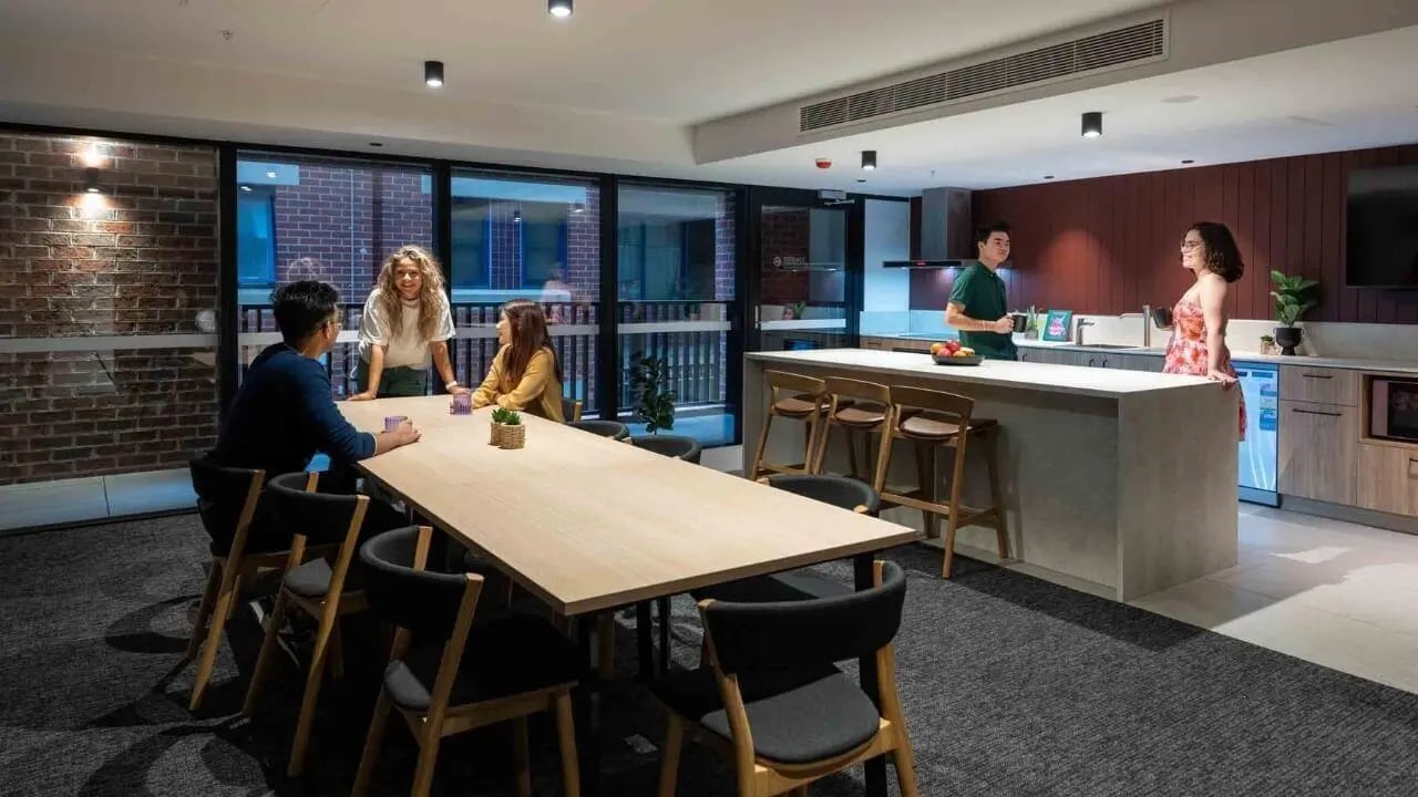 People gathered around long table and kitchen island living room at UniLodge Melbourne Central in Melbourne Student Accommodation