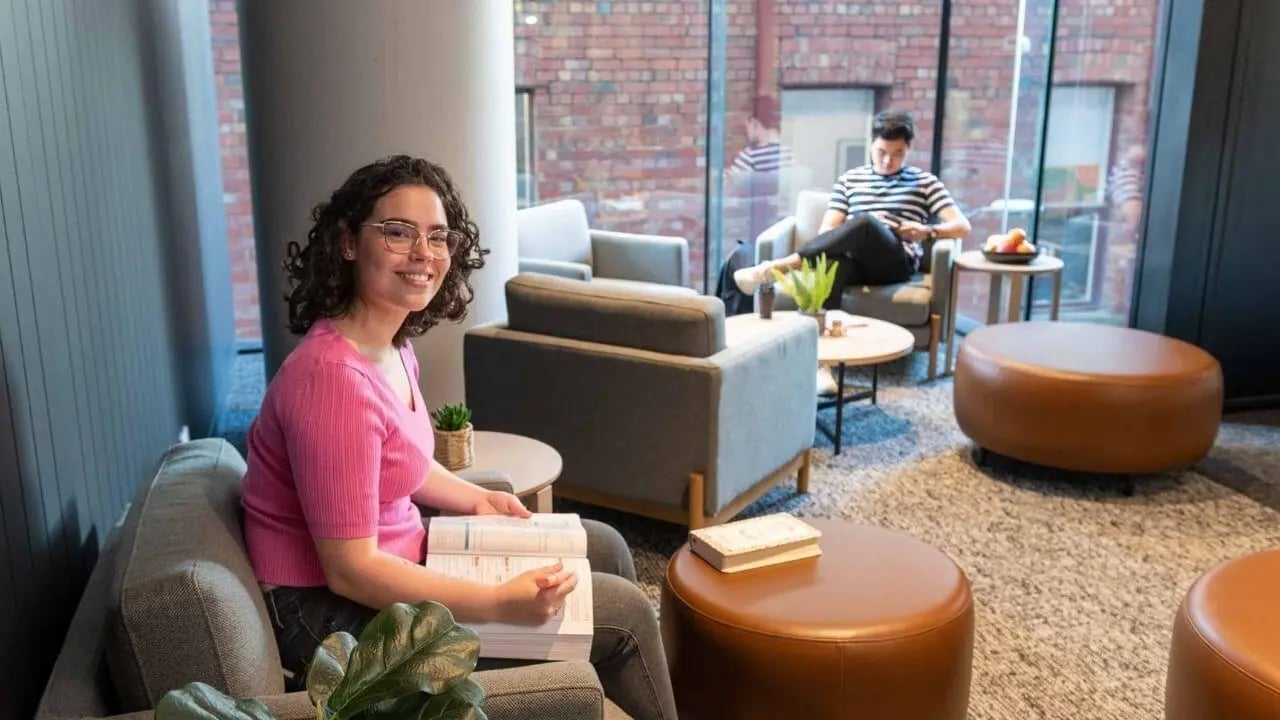 Woman reading with man on phone lounge area at UniLodge Melbourne Central in Melbourne Student Accommodation