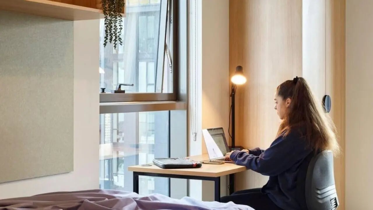 Student studying laptop desk lamp bed study area at Unilodge Melbourne City in Melbourne Student Accommodation