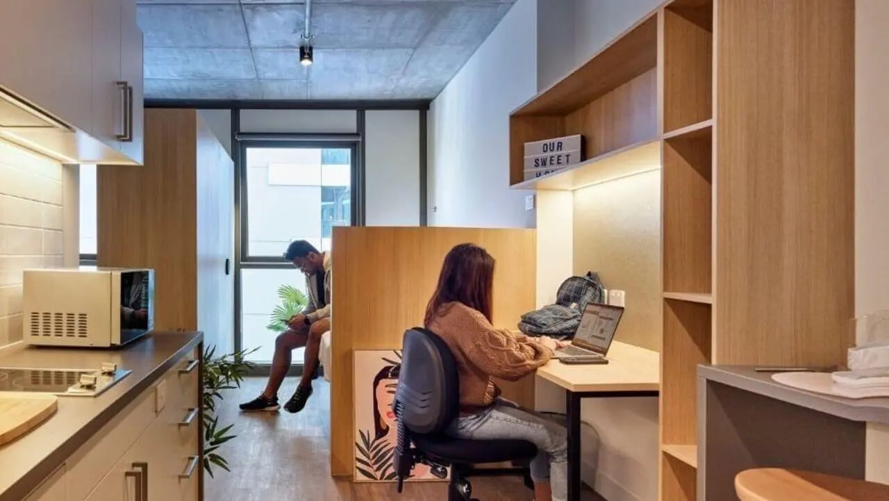 Students study and sit near kitchen and bed at Unilodge Melbourne City in Melbourne Student Accommodation